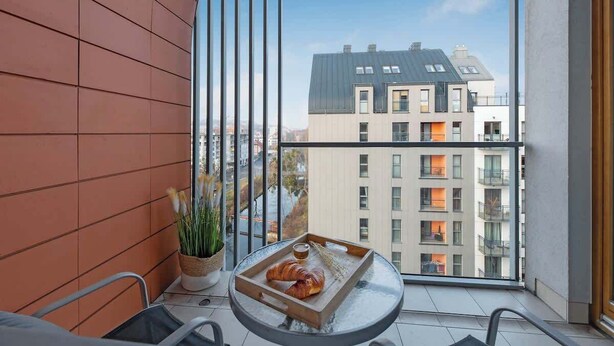 Un balcon avec une table, une chaise et un pot de fleurs.