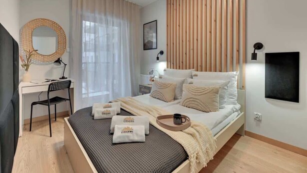 Een moderne slaapkamer met een bed, bureau, stoel en een grote spiegel.