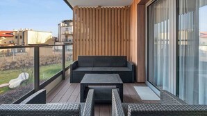Een balkon met een bank, een tafel en rieten stoelen.