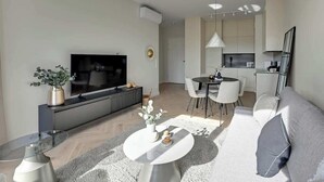 Ein modernes Wohnzimmer mit Flachbildfernseher, Essbereich und Küche.
