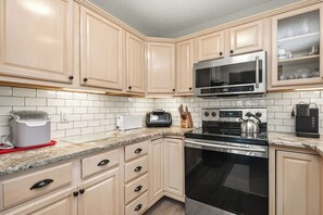 A kitchen with light-colored cabinets, a microwave, a toaster, a kettle, and a coffee maker. - Sea Date Me: Ocean Views, Fenced Backyard (Oak Island)