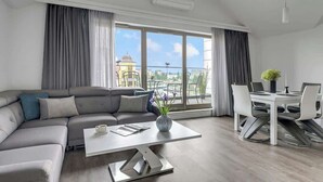 Ein modernes Wohnzimmer mit Sofa, Couchtisch, Esstisch mit Stühlen und einem Balkon mit Blick.