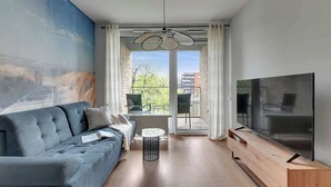 Una sala de estar moderna con un sofá, televisor y un cuadro en la pared.