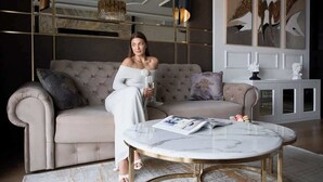 A woman seated on a tufted sofa with a marble coffee table, a chandelier, and abstract wall art. - Deo Plaza 306 | View of the river and the Old Town (Gdańsk)