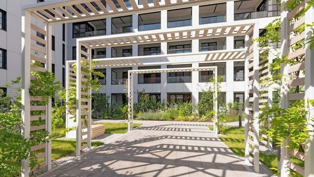 A multi-story building with a covered outdoor area featuring a pergola structure. - Doki G230 | Gdańsk Shipyard & Foodhall (Gdańsk)