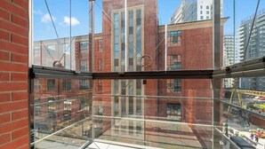A high-rise building with a glass balcony, red brick walls, and a clear view of the cityscape. - Doki G230 | Gdańsk Shipyard & Foodhall (Gdańsk)