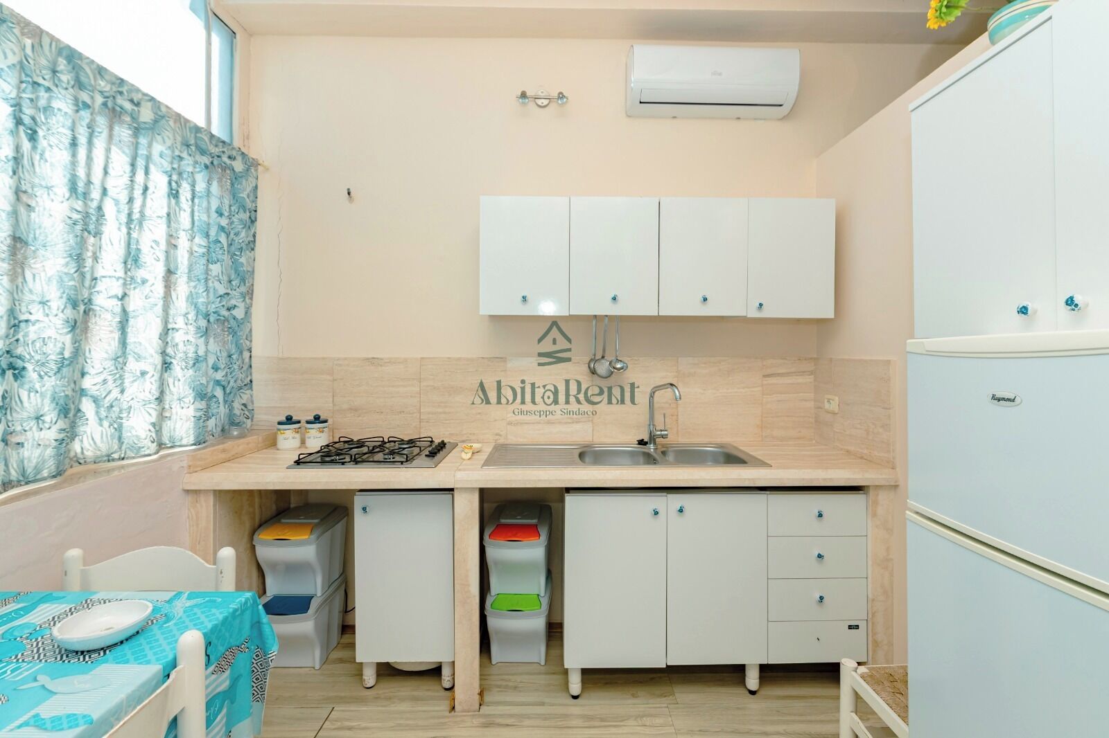Eine kleine Küche mit Gasherd, Spüle und Kühlschrank.