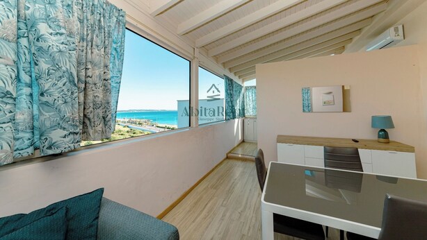 Ein Balkon mit Meerblick, eine Essecke mit Tisch und Stühlen sowie eine Küchenzeile.