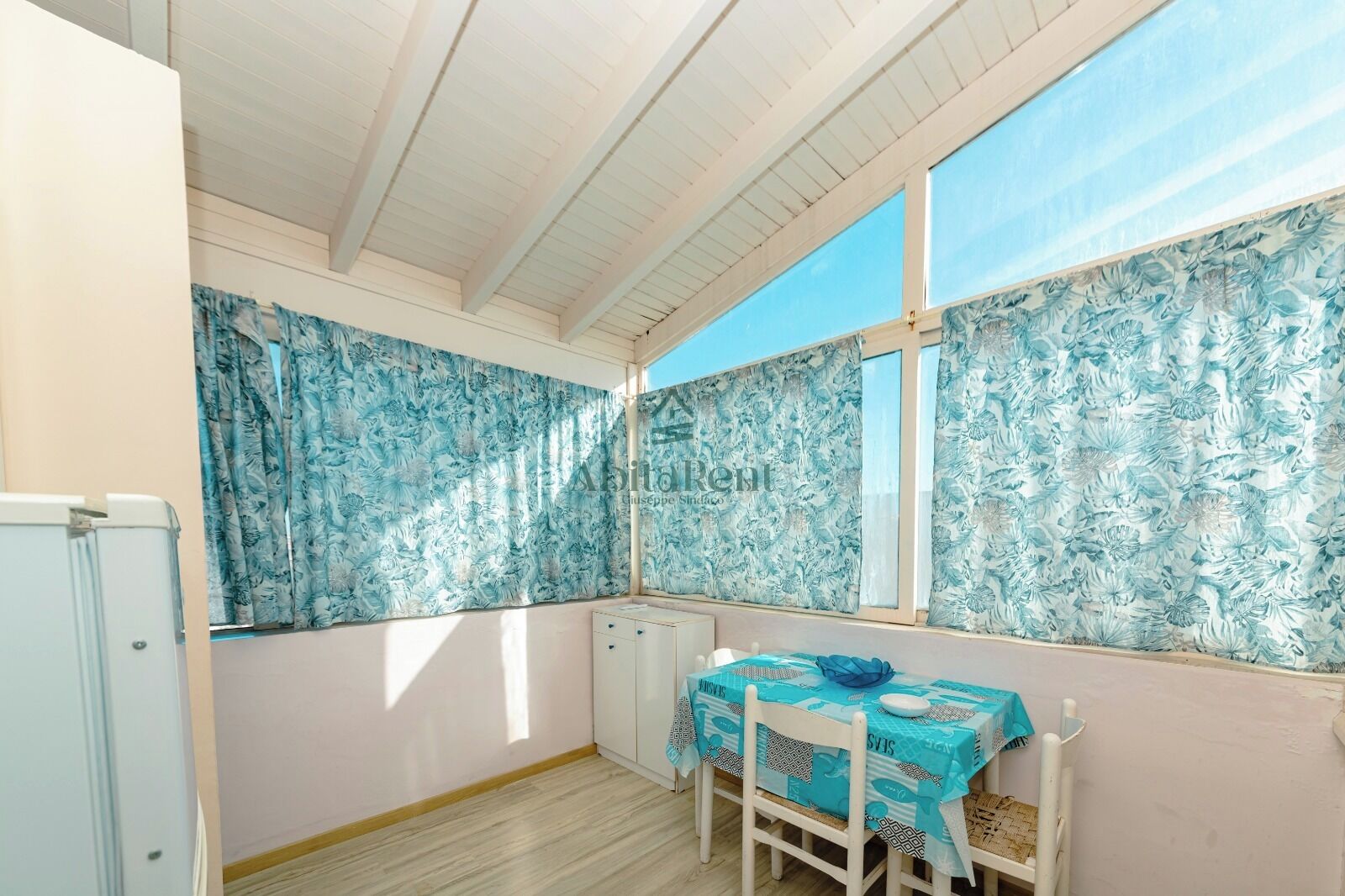 Una habitación con una mesa, sillas, un radiador y una ventana con cortinas.