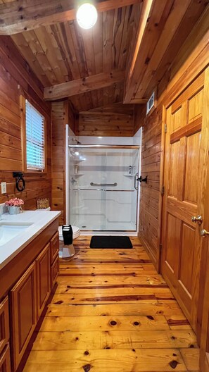 Ein Holzhütten-Innenraum mit Dusche, Holzböden und einem Waschbecken.