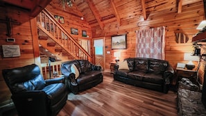 Ein gemütliches Blockhaus-Interieur mit einer Holztreppe, Ledersofas und Holzboden.