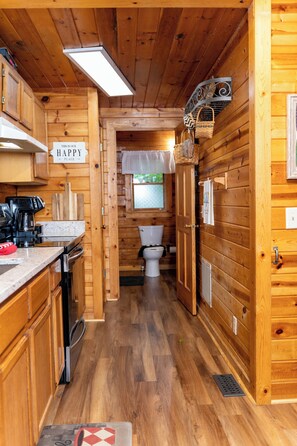 Ein Holzblockhaus-Innenraum mit Küche, Essbereich und Bad.