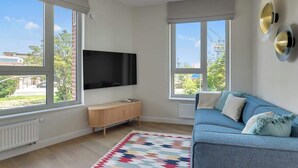 A modern living room with a large TV, a blue sofa, and a colorful rug. - Żurawie B100B | Shipyard | Foodhall Montownia (Gdańsk)