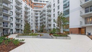 A multi-story residential building with balconies, a central courtyard with trees, and a brick facade. - Żurawie B100B | Shipyard | Foodhall Montownia (Gdańsk)