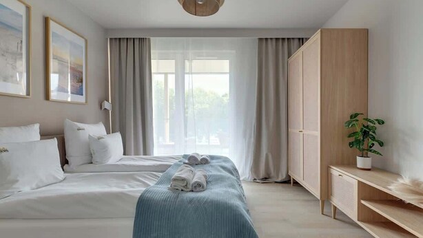 Ein Hotelzimmer mit Bett, Nachttisch, Schrank und einem fenster mit Vorhängen.