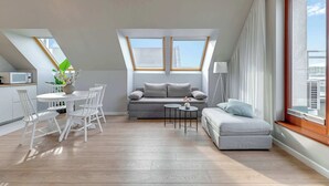 Un appartement moderne de style « loft », comprenant un coin repas, un canapé, une petite table et une grande fenêtre offrant une vue sur la ville.