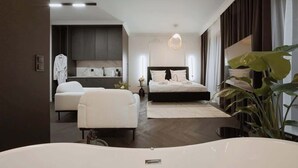 Ein modernes Schlafzimmer mit einem großen Bett, einer Sitzecke, einem Schminktisch und einer üppigen Pflanze.