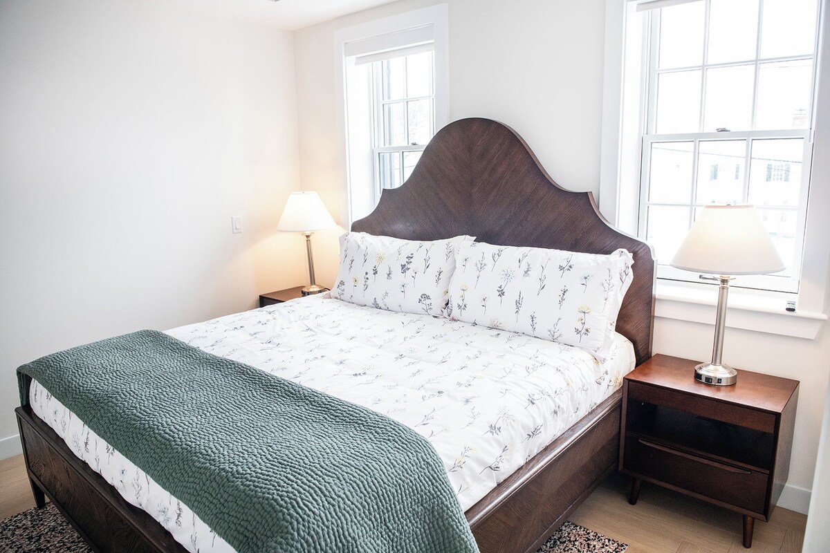 A neatly made bed with a patterned duvet, two bedside lamps, and a nightstand with a lamp.