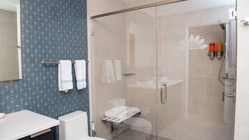 Un baño moderno con cabina de ducha de vidrio, inodoro y lavamanos.