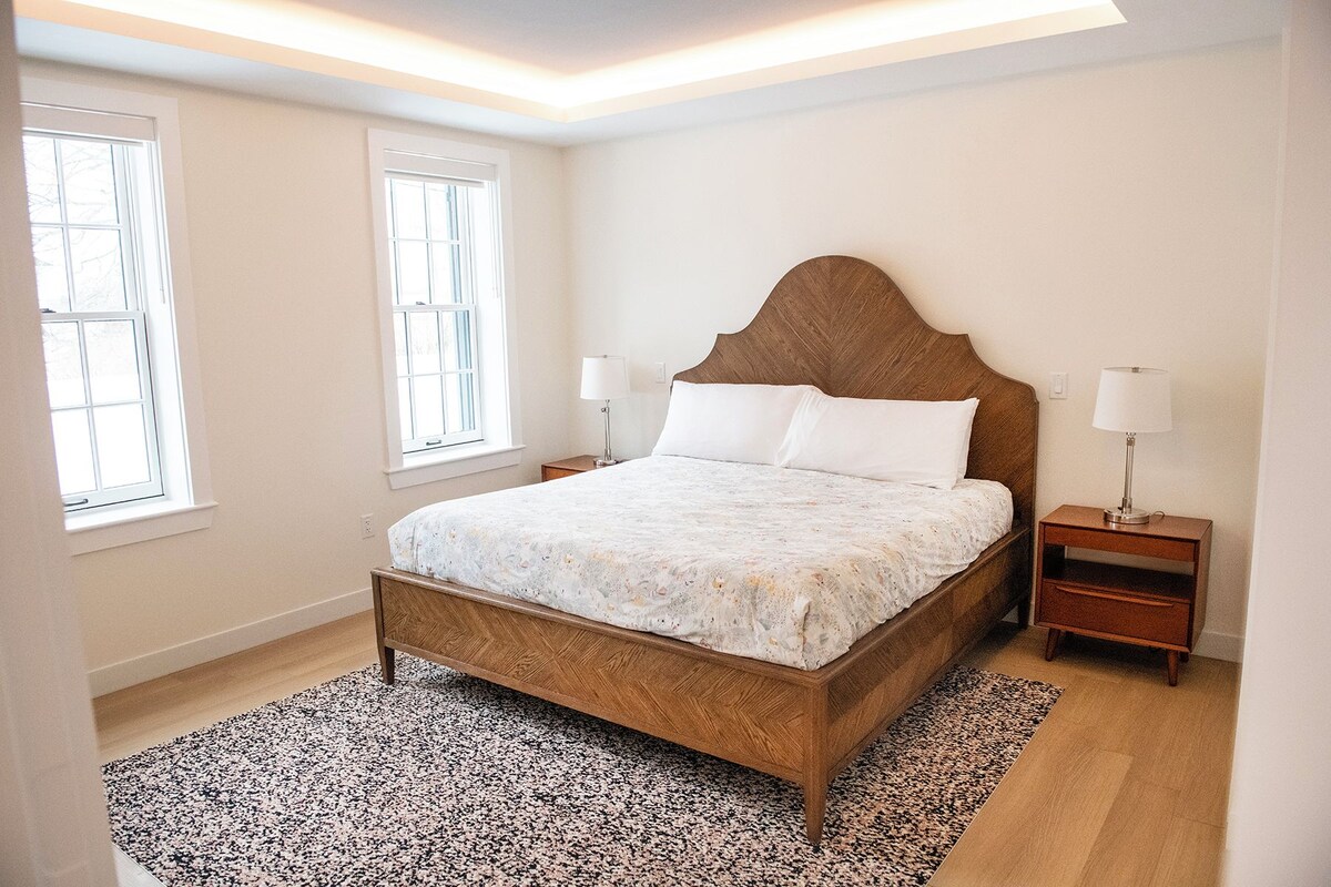 A bedroom with a wooden bed, two bedside tables, and a patterned rug.