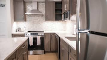 A modern kitchen with stainless steel appliances, wooden cabinets, and a tiled backsplash.