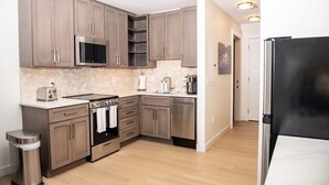 A modern kitchen with wooden cabinets, stainless steel appliances, and a black refrigerator.