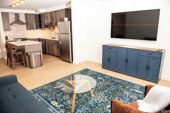A modern kitchen with a central island, stainless steel appliances, and a blue cabinet.