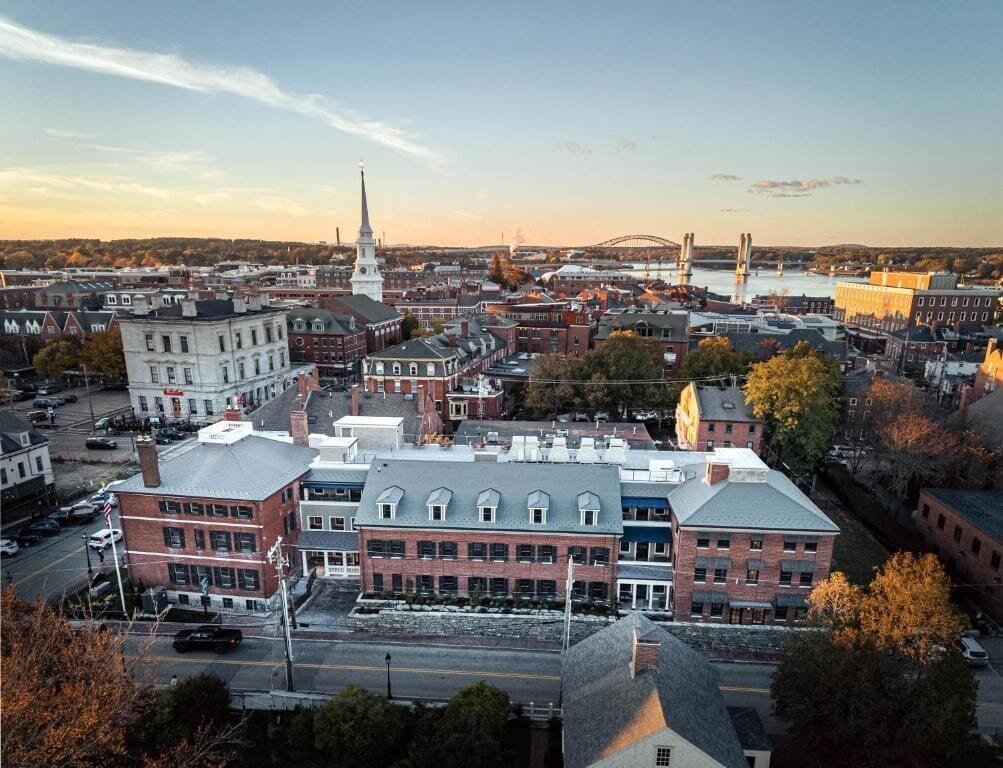 An urban landscape with historic buildings, a prominent church spire, and a bridge in the background.