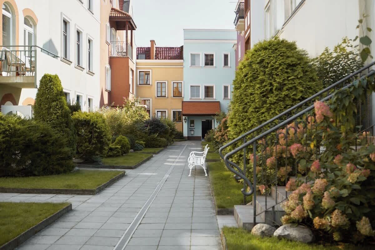 A narrow pathway leading to a building with a staircase on the right.