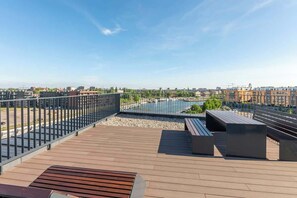 Une terrasse sur le toit offrant une vue sur le paysage urbain, avec une piscine et des espaces de détente modernes en plein air.