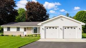 A single-story house with a garage, a front lawn, and a clear sky.