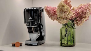 Eine Kaffeemaschine und eine Vase mit Blumen auf einem Regal.
