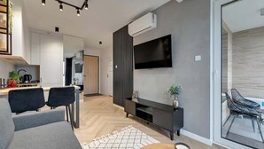 Ein modernes Wohnzimmer mit Sofa, Fernseher und Essbereich.