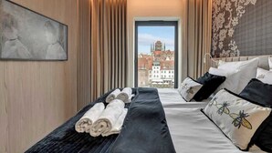Ein Hotelzimmer mit Bett, Handtüchern, einem Fenster mit Stadtblick und einer Wanddekoration.