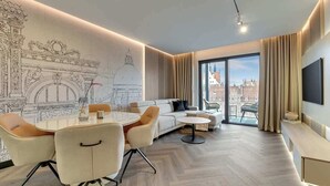 Ein modernes Wohnzimmer mit Essbereich, einer Couch, einem Fernseher und einem großen Fenster mit Blick auf die Stadt.