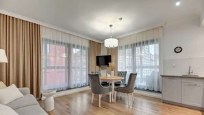 Una sala de estar moderna con sofá, mesa de comedor, sillas y televisor.
