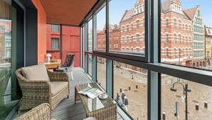 Un balcón con mobiliario de mimbre, una mesa y vistas a un edificio histórico.