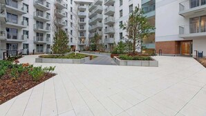 A multi-story residential building with balconies, a central courtyard with plants, and a brick facade. - Żurawie B127A | Shipyard | Foodhall Montownia (Gdańsk)