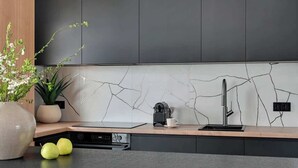 A modern kitchen with a marble backsplash, a built-in oven, and a coffee machine. - Żurawie B127A | Shipyard | Foodhall Montownia (Gdańsk)