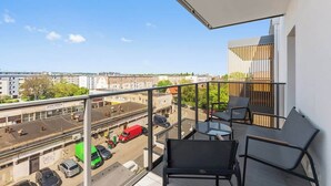 Ein Balkon mit Blick auf eine Stadtstraße, einem Tisch und zwei Stühlen.