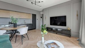 En moderne stue med spiseplads, et fladskærms-tv og en pejs.