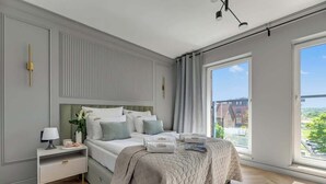 Et moderne soveværelse med en stor seng, sengeborde og udsigt over byen.