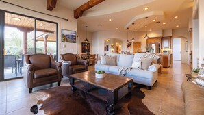 A spacious living room with leather furniture, a coffee table, and a cowhide rug. - Infinity Pool, Mountain Views and Putting Green (Scottsdale)
