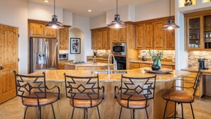 A kitchen with wooden cabinets, stainless steel appliances, and pendant lighting. - Infinity Pool, Mountain Views and Putting Green (Scottsdale)