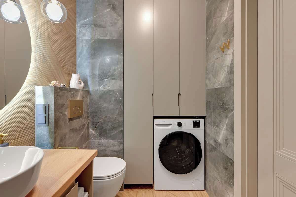 Une petite salle de bain comprenant un lavabo, des toilettes et un lave-linge.