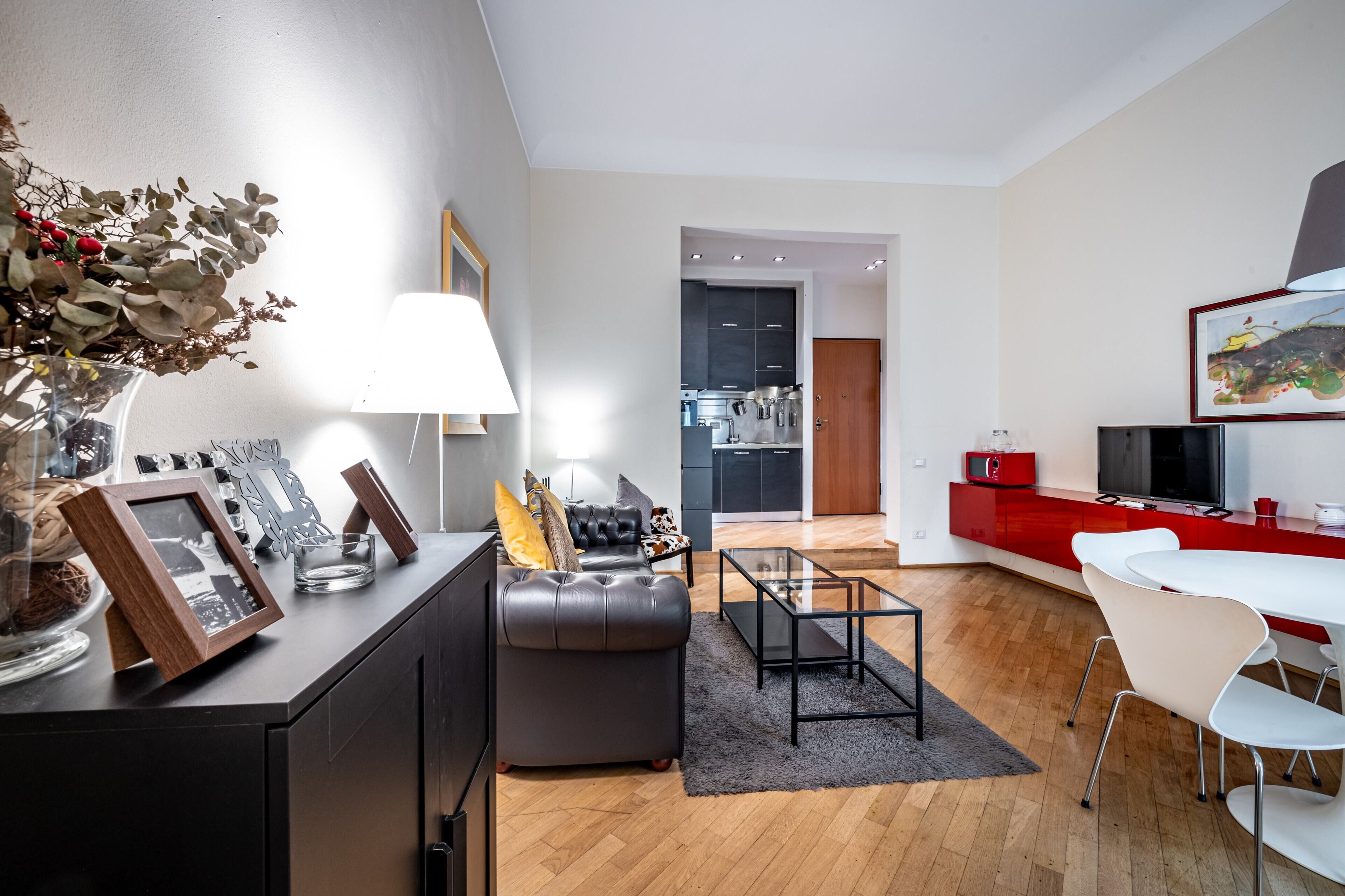 A modern living room with a sofa, a coffee table, and a dining area with chairs.
