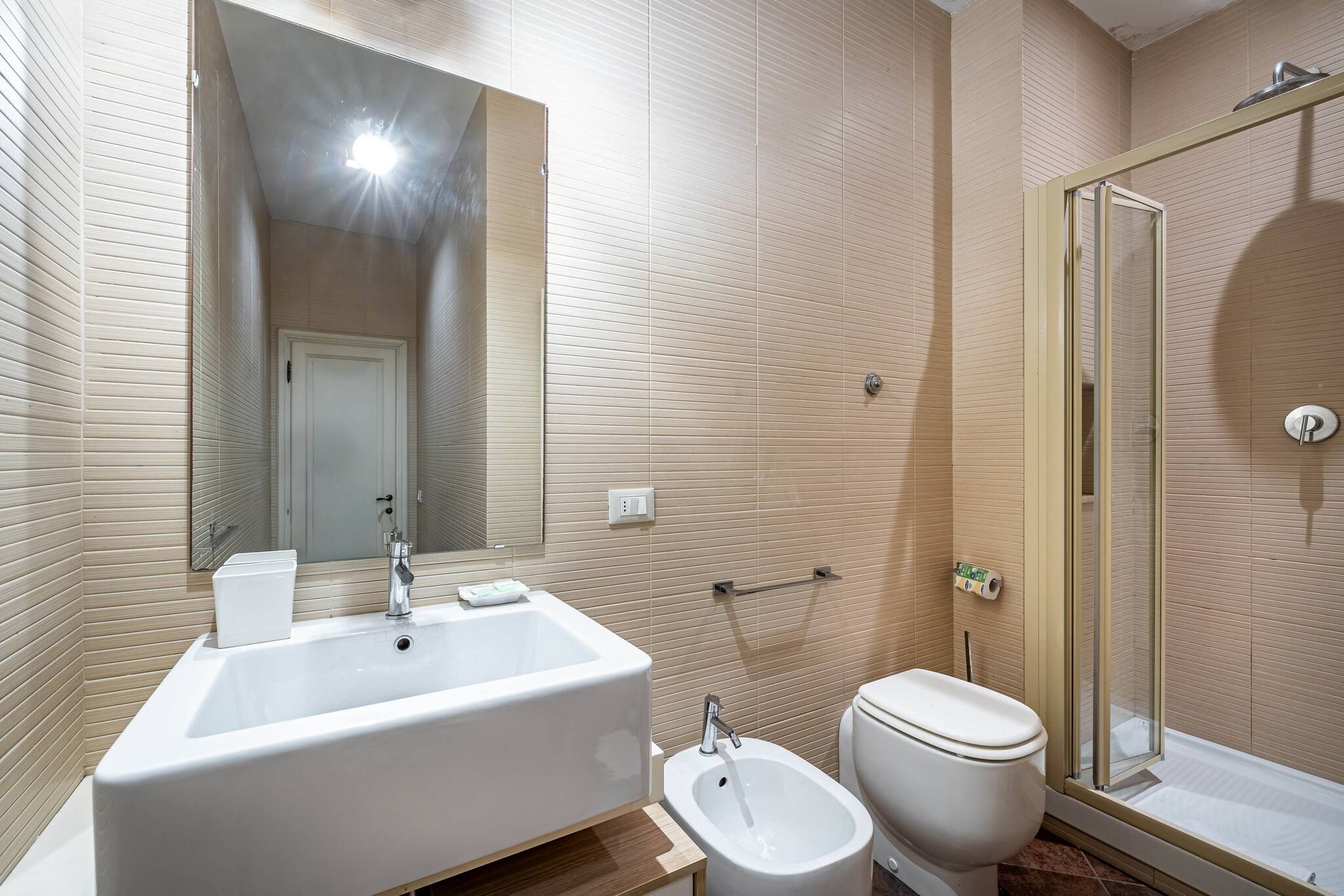 Une salle de bain comprenant un grand lavabo, un bidet, des toilettes, une douche et un miroir.