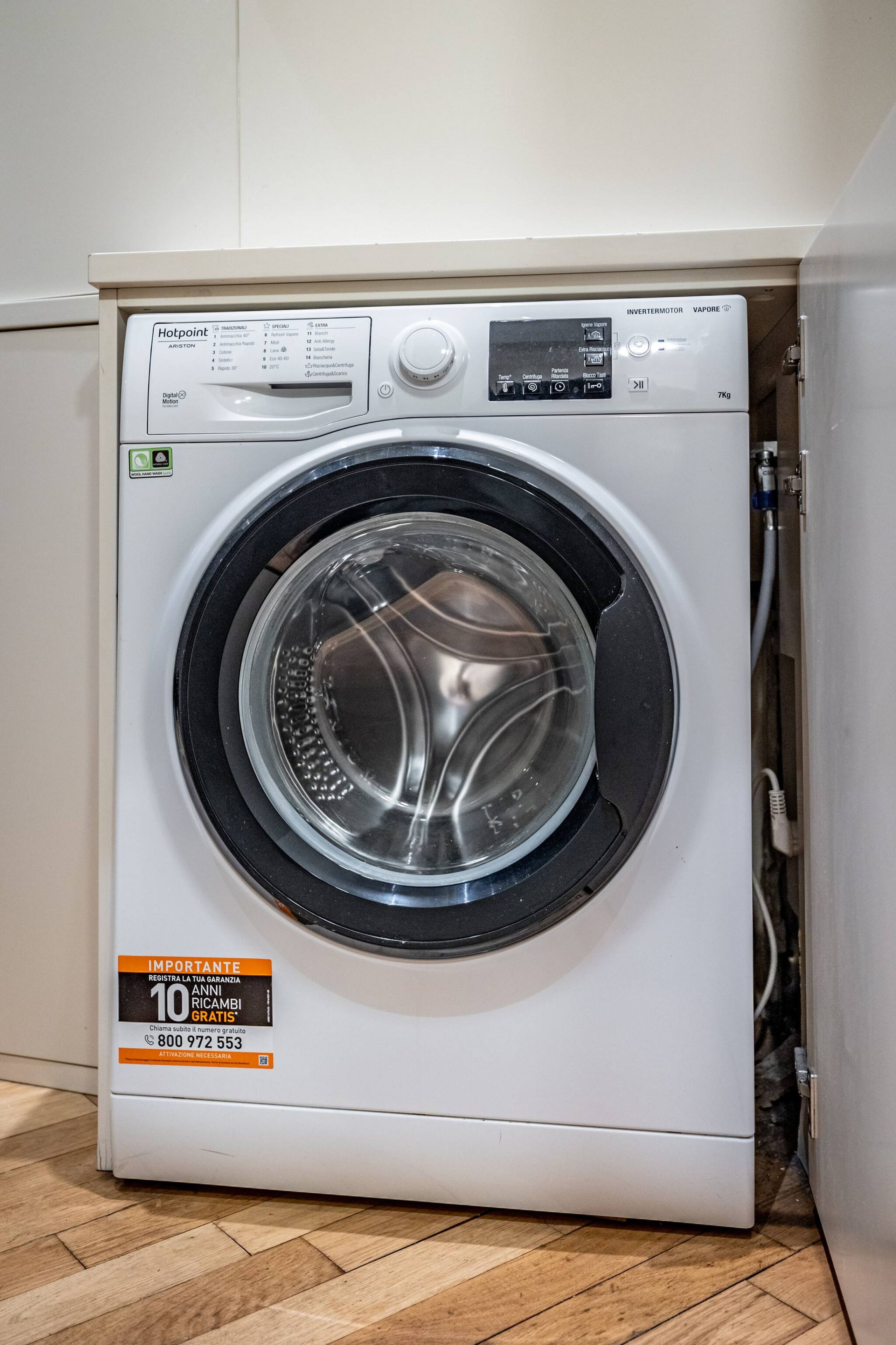 A front-loading washing machine with a digital display and a 10-year free service offer.