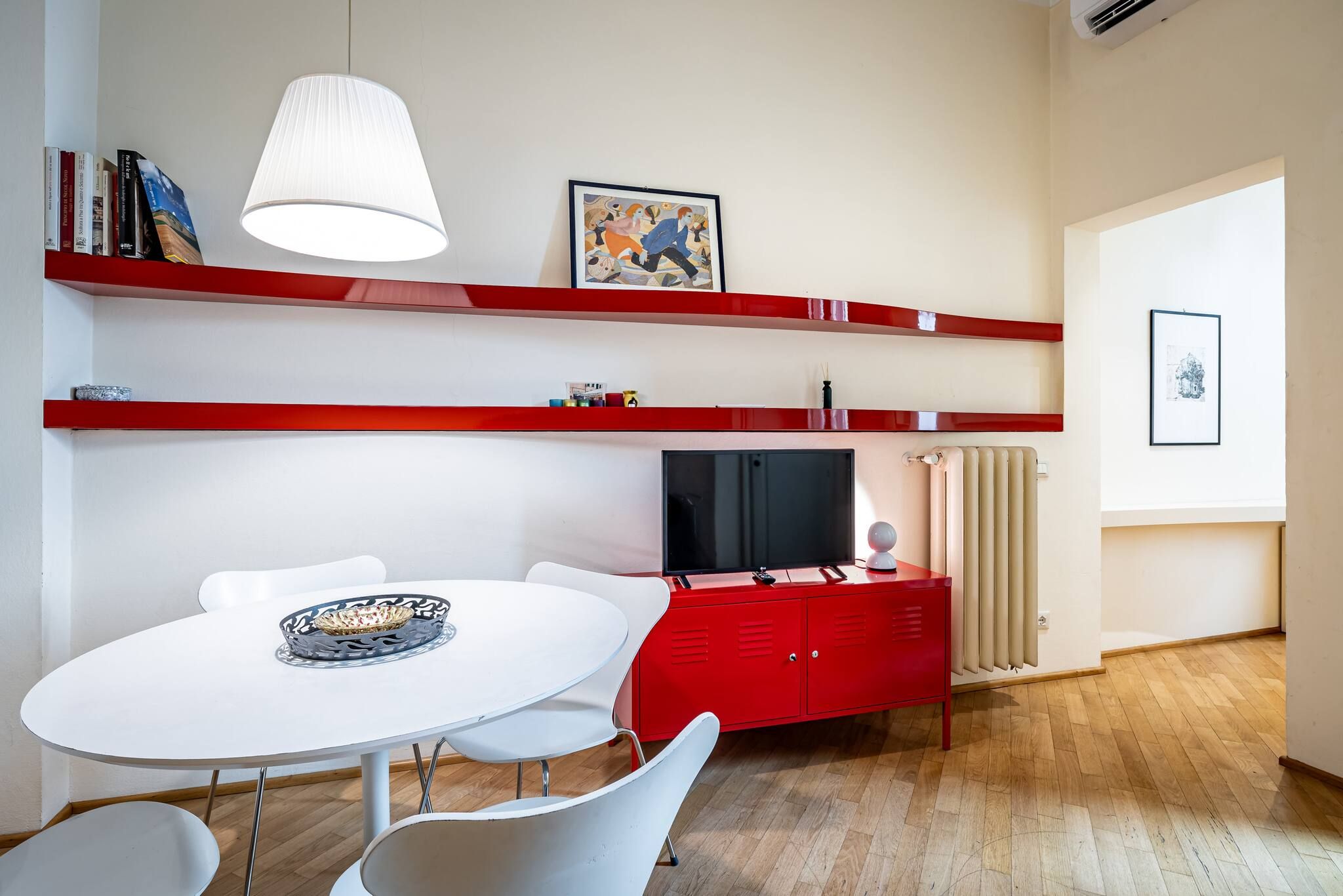 Un salon moderne avec une table ronde blanche, des meubles rouges et un téléviseur.