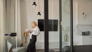 Un salon moderne avec un téléviseur à écran plat, un canapé, un fauteuil à motifs et des luminaires suspendus.